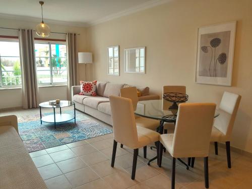 ein Wohnzimmer mit einem Sofa, einem Tisch und Stühlen in der Unterkunft Palmeiras Apartement - T1 com Piscina in Baleal