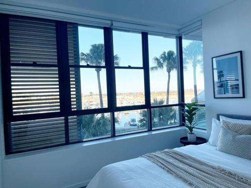 - une chambre avec un grand groupe de fenêtres et un lit dans l'établissement Luxury Apartment in Shell Cove, à Shellharbour