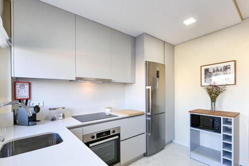 Una cocina con gabinetes blancos y un refrigerador de acero inoxidable. en Casa do Couteiro, en Braga