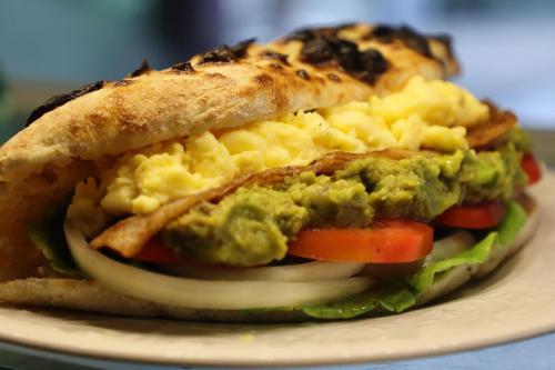 a sandwich with guacamole and vegetables on a plate at Ziggy Stardust in Ko Phayam
