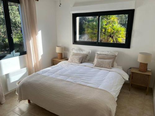 - une chambre avec un lit blanc et 2 fenêtres dans l'établissement Maison Jardin d'Agrumes - Lozari, à Belgodère