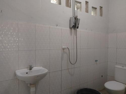 uma casa de banho branca com um lavatório e um WC em Maeza Homestay em Kuta
