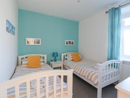 2 camas en una habitación con paredes azules en The Old Smithy en Morpeth
