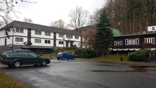 une voiture garée dans un parking en face d'un bâtiment dans l'établissement Hotel Koliba, à Vrbno pod Pradědem