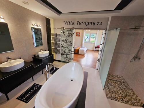 ein Badezimmer mit zwei Waschbecken, einer Badewanne und einer Dusche in der Unterkunft Villa 5*, 15 personnes, Piscine à 20 min de Genève in Juvigny