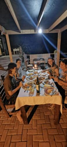 a group of people sitting at a table with food at Kaza Ladera in Seladinha