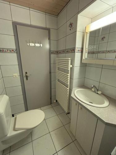 a white bathroom with a toilet and a sink at Croix 1 in Le Noirmont