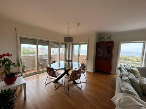 uma sala de estar com uma mesa de vidro e um sofá em Apartamento vista mar em Labruge
