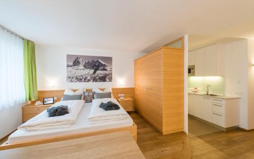 a bedroom with a large white bed and a kitchen at Avita - suites to relax in Ortisei