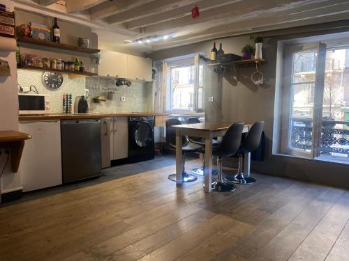 a kitchen with a table and chairs in a room at STUDIO CANAL SAINT MARTIN in Paris