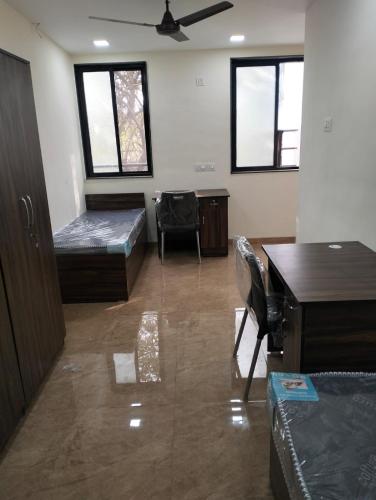 a room with a bed and a desk and windows at Agrawal Stay Viman Nagar (Female Only) in Pune