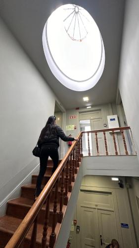 a woman is standing on the railing of a staircase at A Beira Hostel in Aveiro