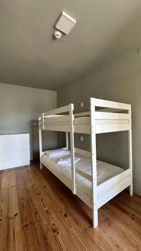 two white bunk beds in a room with wooden floors at A Beira Hostel in Aveiro