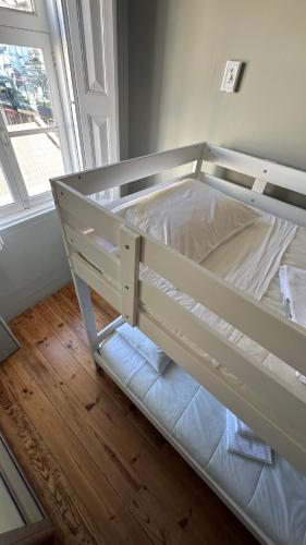 a white bunk bed in a room with a window at A Beira Hostel in Aveiro