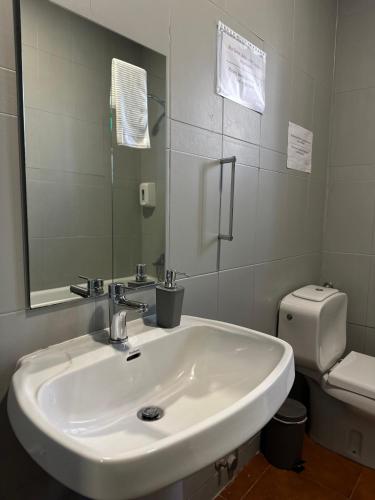 a bathroom with a white sink and a toilet at A Beira Hostel in Aveiro