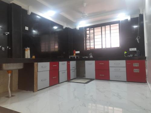 eine Küche mit roten und weißen Schränken und einem Fenster in der Unterkunft Agrawal Stay Viman Nagar (Female Only) in Pune