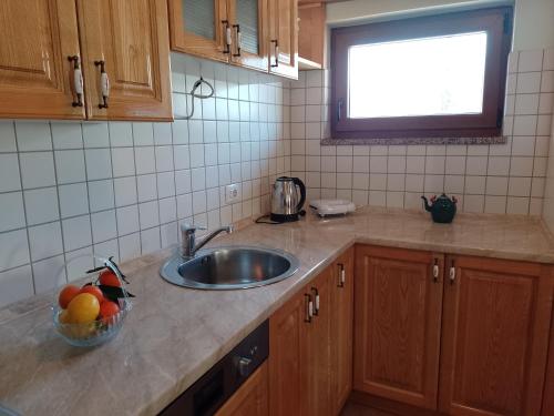 a kitchen with a sink and a bowl of fruit on the counter at Apartman Centar Fužine in Fužine