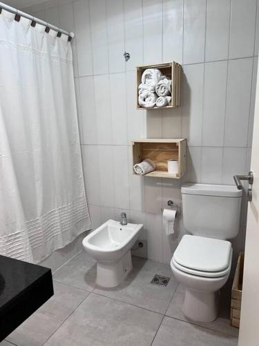 a white bathroom with a toilet and a sink at Departamento Lombardo in Lobos