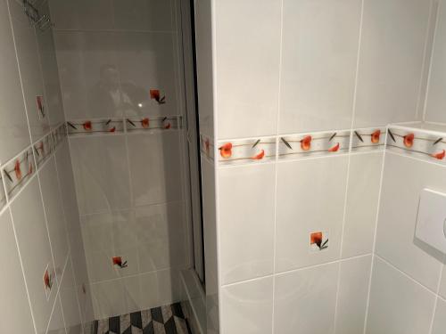 a shower with white tiled walls and orange cups at Penzion Sokolov 1 in Sokolov
