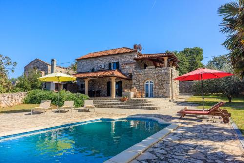 a house with a swimming pool in front of a house at Villa Karlo - Sabljići - Island of Krk - traditional stone villa with pool in Sveti Anton