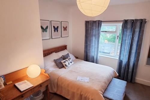 a bedroom with a bed and a desk and a window at The Flat at Conway House in Overstrand