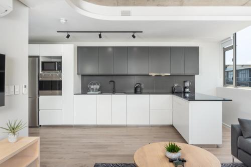 a kitchen with white cabinets and a table in a room at The Quarter Luxury Apartments in Cape Town