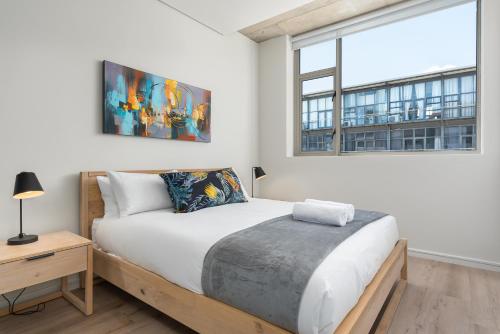 a bedroom with a bed and a large window at The Quarter Luxury Apartments in Cape Town