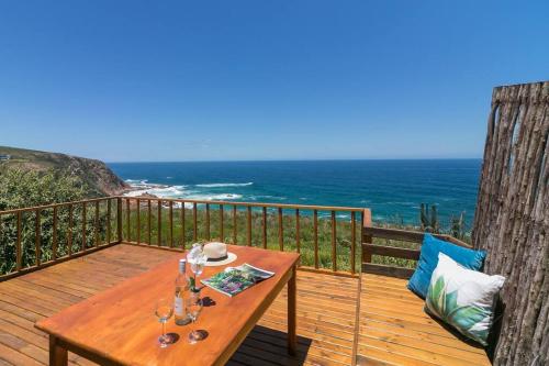 a wooden deck with a table with a view of the ocean at Knysna Views - Pezula Seashore - Sea-facing in Knysna