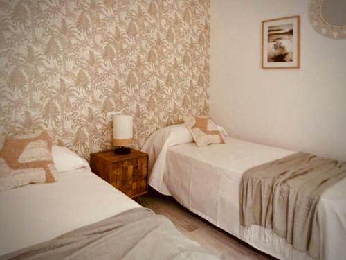 a bedroom with two beds and a wall with wallpaper at Casa Mama Carina A in Agüimes