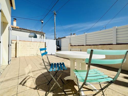 deux chaises et une table sur une terrasse dans l'établissement Maison de vacances au calme quartier de la Chaume 5 pers, à Les Sables-dʼOlonne
