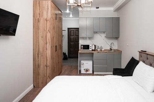 1 dormitorio con 1 cama blanca y cocina en Deluxe Park Z hotel, en Almaty
