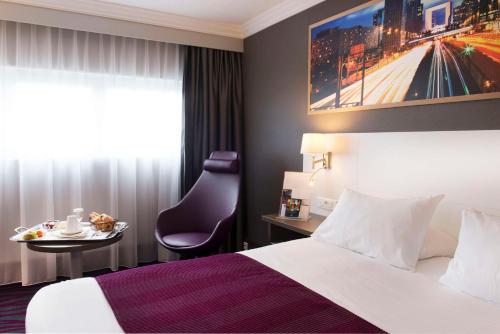 a hotel room with a bed and a table with a chair at Best Western Plus Paris Orly Airport in Rungis