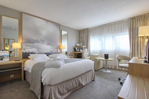 ランジスにあるホリデイ イン オルリーの大きなベッドとデスクが備わるホテルルームです。