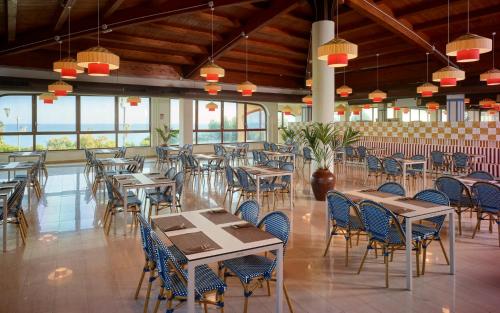una sala da pranzo con tavoli, sedie e finestre di Serenusa Resort a Licata