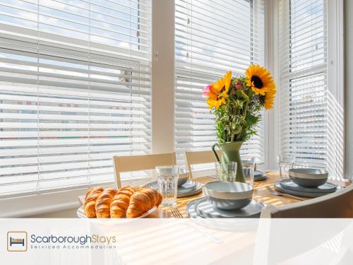 a dining room table with a vase of sunflowers at Hampton House - Lovely and Spacious 2 Bedroom Apartment - WITH FREE PARKING in Scarborough