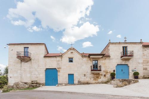an old stone building with blue doors and windows at Pazo da Pena Manzaneda in Manzaneda