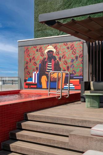 a painting of a person sitting on a bench on a wall at Radisson RED Hotel Johannesburg Rosebank in Johannesburg
