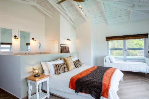 a white bedroom with a bed and a window at Kangela 2 in Ponta Malongane