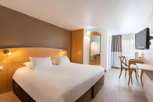 a hotel room with a large bed and a desk at Sure Hotel by Best Western Plaisir in Plaisir