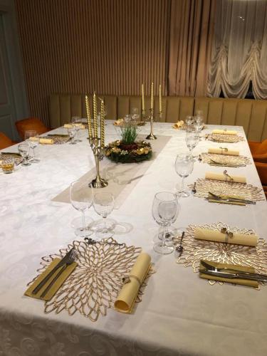 a table with a white table cloth with wine glasses at Pensiunea Magic in Băile Govora