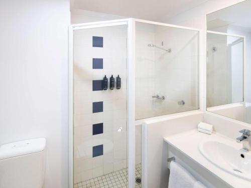 a white bathroom with a shower and a sink at Mercure Sydney Manly Warringah in Sydney