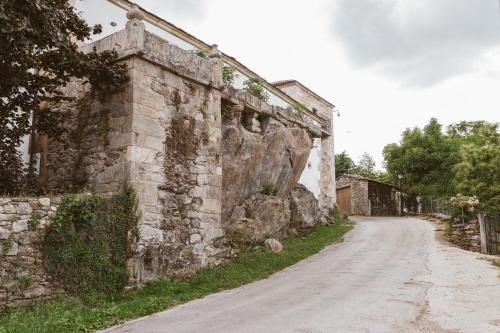 an old stone wall next to a dirt road at Pazo da Pena Manzaneda in Manzaneda