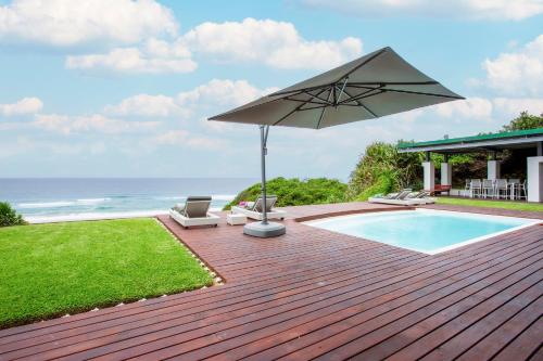 a wooden deck with an umbrella and a swimming pool at Kangela 2 in Ponta Malongane