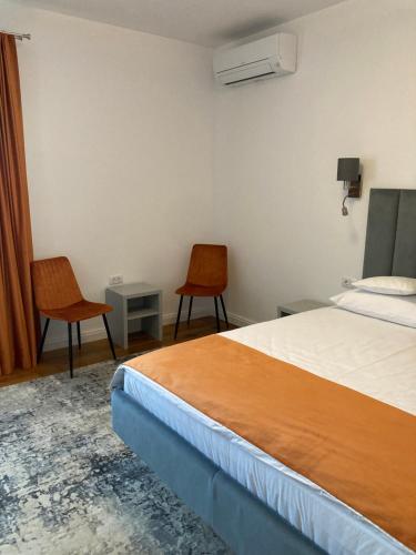a hotel room with a bed and two chairs at Pensiunea Magic in Băile Govora