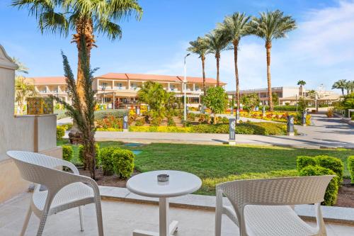 a patio with chairs and a table and palm trees at Pickalbatros Aqua Park Sharm El Sheikh in Sharm El Sheikh