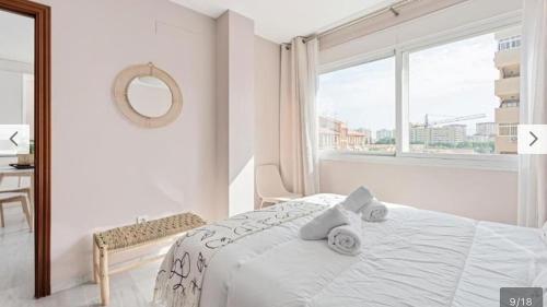 a white bedroom with a bed and a large window at Luis Braille Apt in Málaga