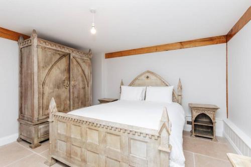 een slaapkamer met een groot bed en een houten kast bij Bix Lodge in Henley on Thames