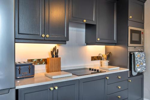 a kitchen with dark blue cabinets and a stove at Finest Retreats - The Old Counting House in Gweek
