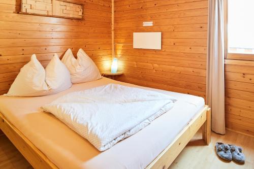 een slaapkamer met een bed in een houten muur bij Blockhütte Aifnerblick in Ried im Oberinntal