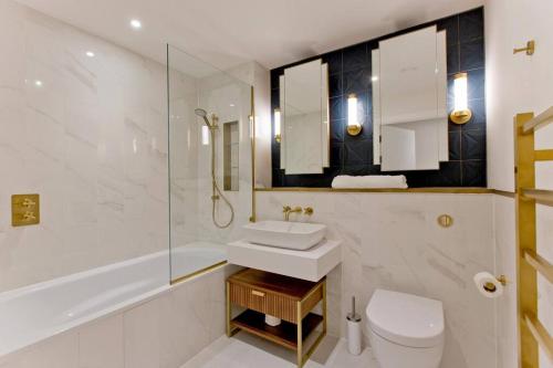 La salle de bains est pourvue d'un lavabo, de toilettes et d'une douche. dans l'établissement Immaculate new 1 bed AC & pool Chelsea, à Londres
